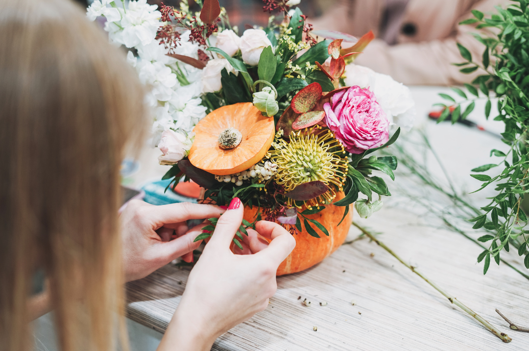 Women arranging a fall floral arrangement.